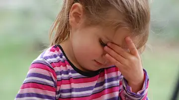 Una niña con la mano en la frente Una niña con la mano en la frente
