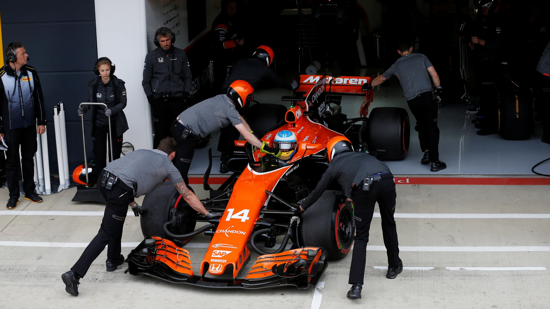 Fernando Alonso mete su coche en el box con la ayuda de sus mecánicos