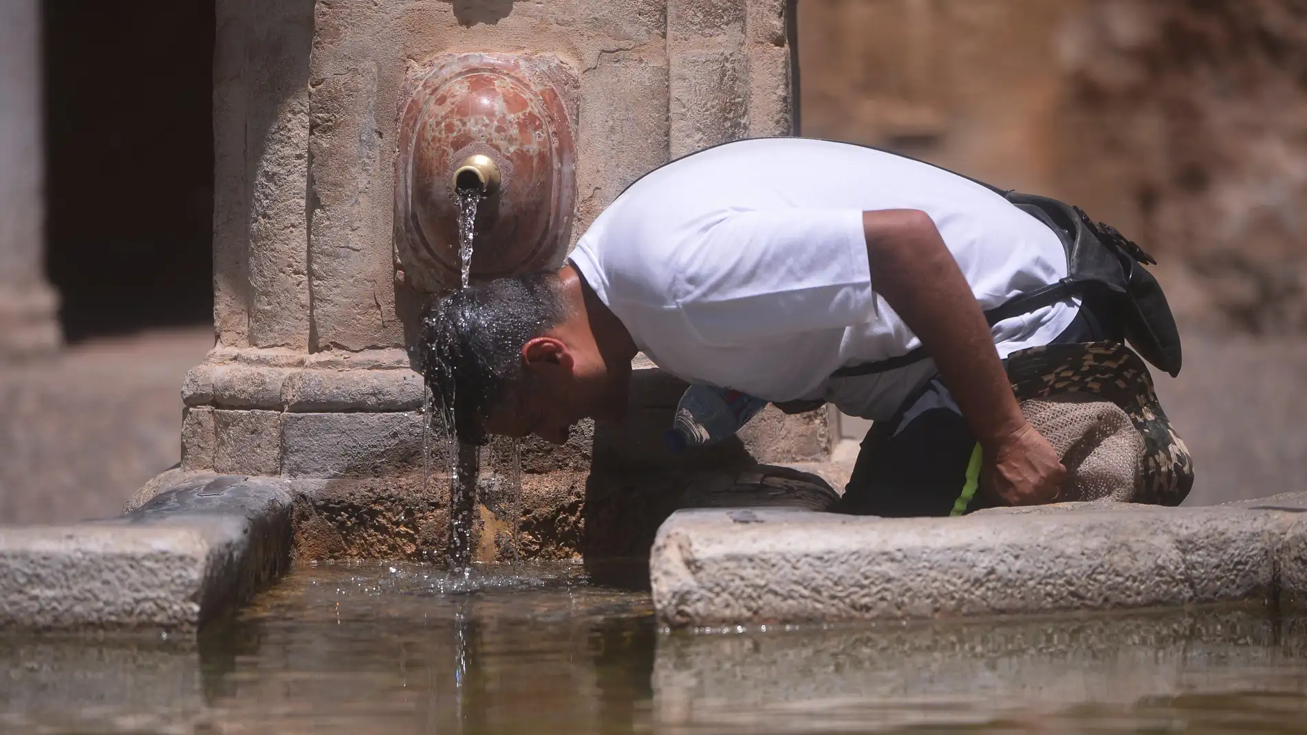 Un hombre combate el calor en una fuente