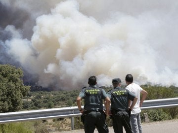 Agentes de la Guardia Civil observan el incendio forestal declarado en la Nacional 122