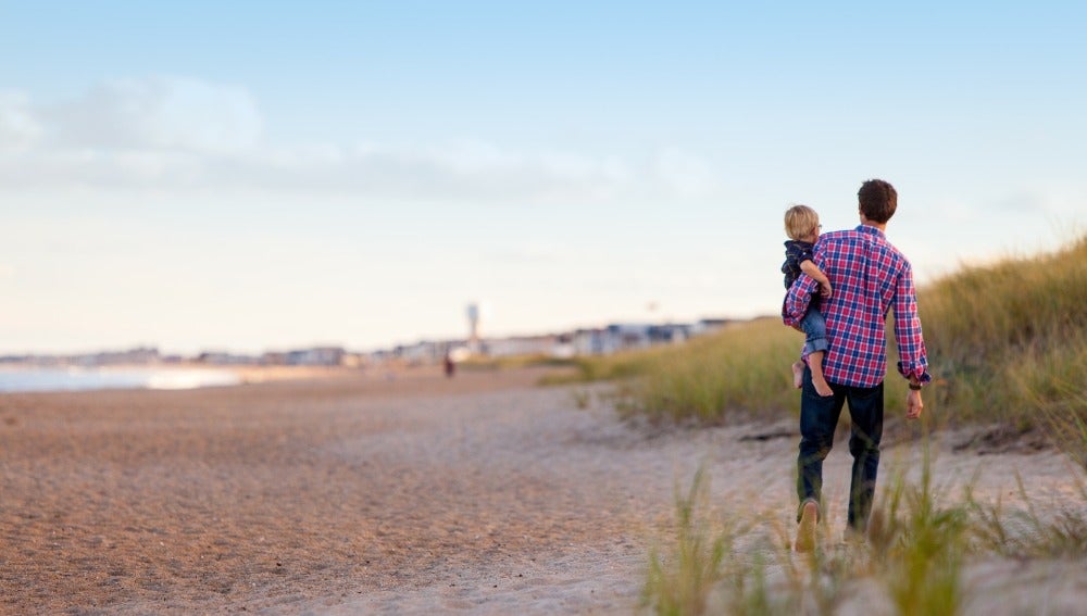 Padre caminado por la playa con su hijo