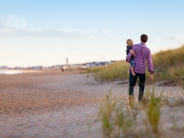 Padre caminado por la playa con su hijo