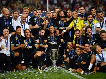 Los jugadores del Real Madrid se sientan sobre el césped con la Supercopa de Europa