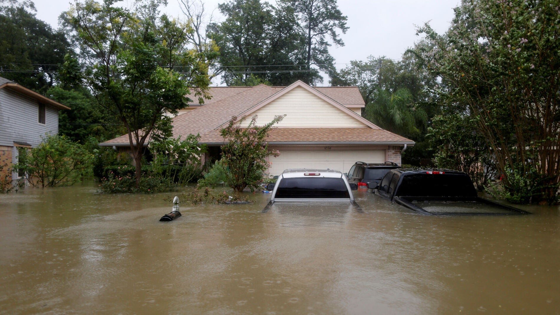Casas y coches parcialmente sumergidos por las aguas a causa de la tormenta tropical Harvey en el este de Houston, Texas