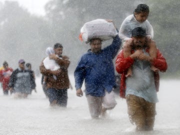 Los residentes caminan por zonas inundadas que deja la tormenta tropical Harvey en Beaumont Place, Houston