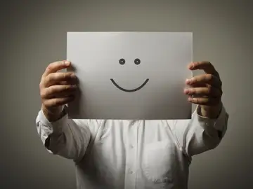 Un hombre sujeta una cara sonriente Un hombre sujeta una cara sonriente