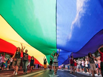 Varias personas portan una bandera arcoriris gigante