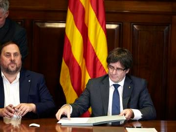 El presidente de la Generalitat, Carles Puigdemont, acompañado por el vicepresidente Oriol Junqueras, firma la convocatoria de referéndum en el Parlament