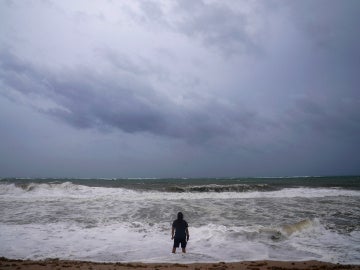 Imagen de archivo de un hombre en una playa con el cielo nuboso