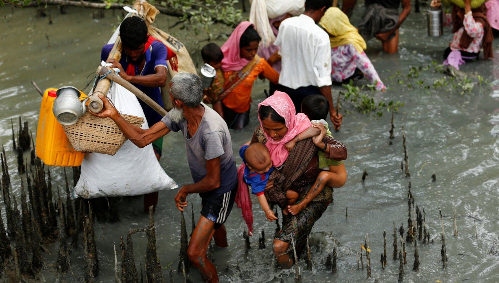 Refugiados Rohingya caminan a través del agua después de cruzar la frontera en barco a través del río Naf en Teknaf en Bangladesh