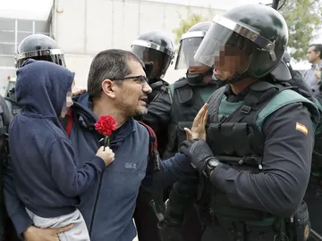Un padre con su hijo en brazo conversa con un guardia civil ante uno de los colegios Un padre con su hijo en brazo conversa con un guardia civil ante uno de los colegios