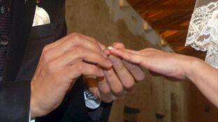 Manos de una pareja intercambiando los anillos en la ceremonia de su boda