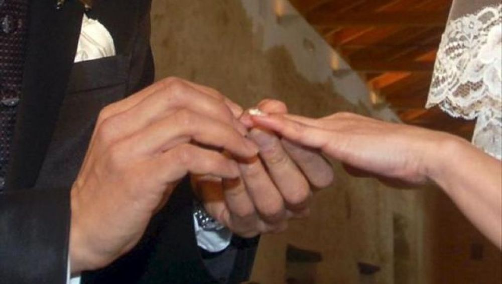 Manos de una pareja intercambiando los anillos en la ceremonia de su boda