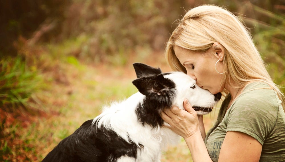 Una mujer dándole un beso a su perro