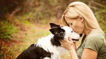 Una mujer dándole un beso a su perro