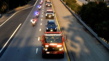 Comitiva de vehículos de bombero transportando el cuerpo del compañero fallecido