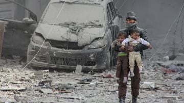 Un ciudadanos sirio lleva consigo a dos niños heridos 