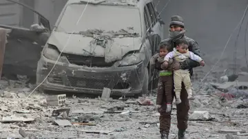 Un ciudadanos sirio lleva consigo a dos niños heridos Un ciudadanos sirio lleva consigo a dos niños heridos