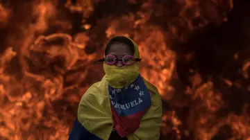 Una activista de la oposición venezolana se cubre la cara frente al fuego de la barricadas Una activista de la oposición venezolana se cubre la cara frente al fuego de la barricadas