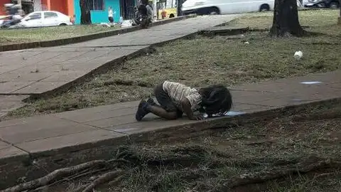 Una niña bebiendo de un charco Una niña bebiendo de un charco