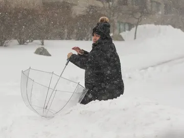 Una mujer camina en medio de nieve durante una tormenta de nieve Una mujer camina en medio de nieve durante una tormenta de nieve