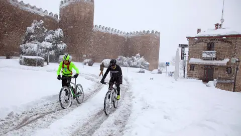 Ciclistas ante la muralla de Ávila La gran nevada, en imágenes