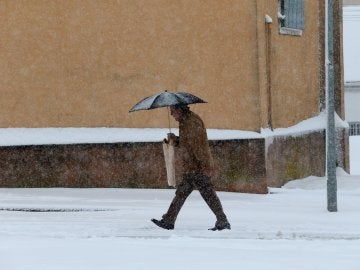 Un hombre camina bajo la nieve en la localidad salmantina de Guijuelo