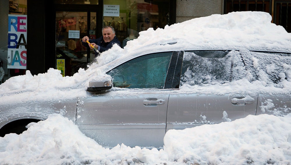 Un hombre retira la capa de nieve de un coche