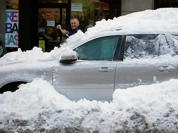 Un hombre retira la capa de nieve de un coche Un hombre retira la capa de nieve de un coche