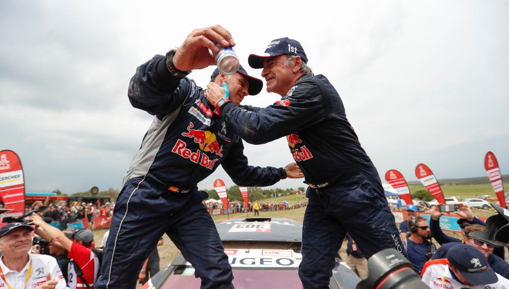 Lucas Cruz y Carlos Sainz se abrazan tras ganar el Dakar