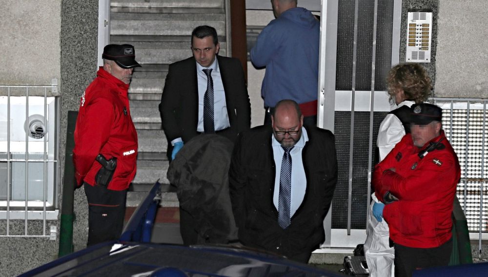 Miembros de los servicios funerarios con el cuerpo de uno de los miembros del matrimonio