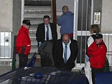 Miembros de los servicios funerarios con el cuerpo de uno de los miembros del matrimonio Miembros de los servicios funerarios con el cuerpo de uno de los miembros del matrimonio