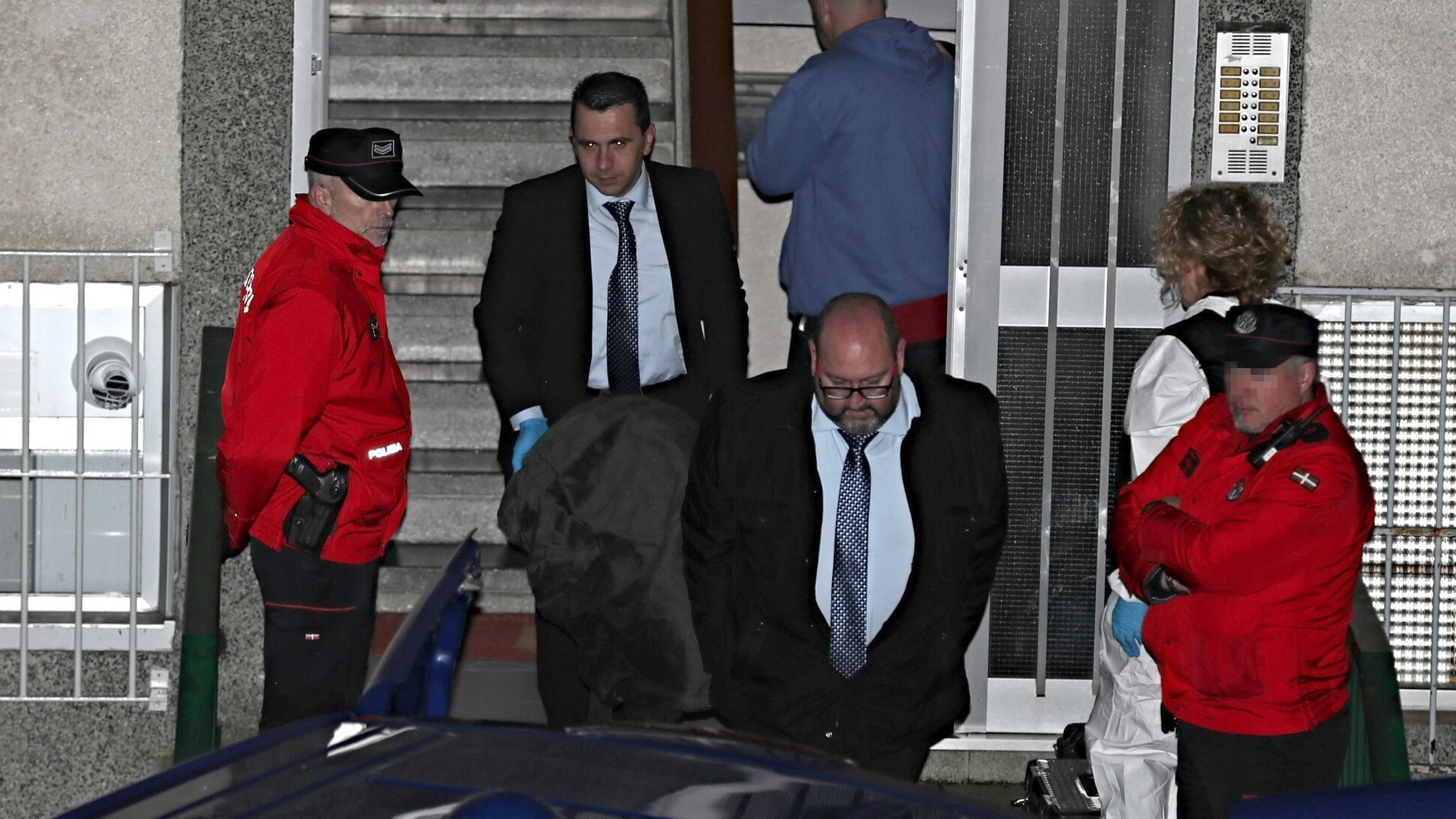 Miembros de los servicios funerarios con el cuerpo de uno de los miembros del matrimonio Miembros de los servicios funerarios con el cuerpo de uno de los miembros del matrimonio