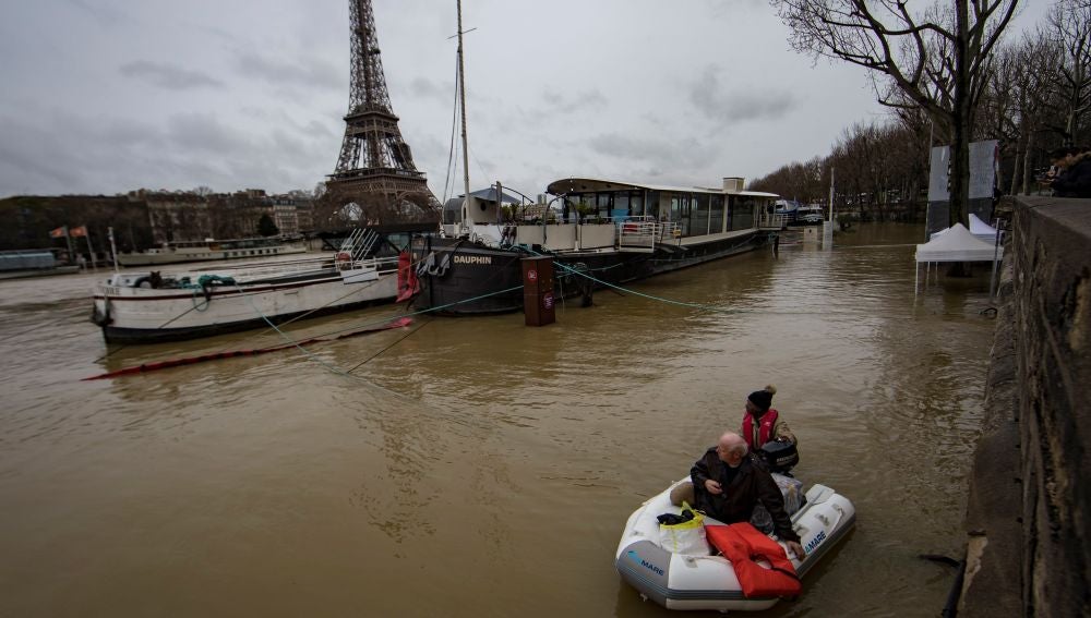  Un hombre transporta a un pasajero en un bote en el desbordado río Sena