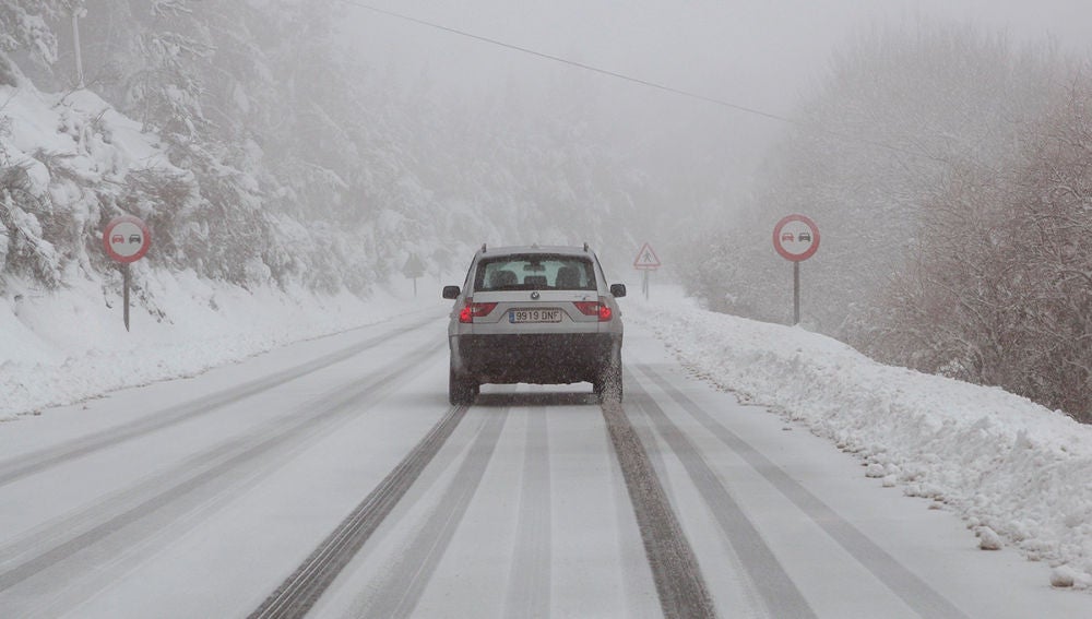 Un vehículo circula por una carretera nevada