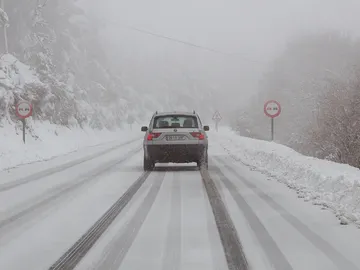 Un vehículo circula por una carretera nevada Un vehículo circula por una carretera nevada