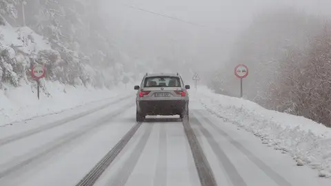 Un vehículo circula por una carretera nevada Un vehículo circula por una carretera nevada