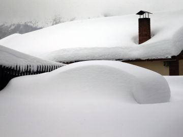 Un vehículo cubierto de nieve, en el pueblo asturiano de Pajares
