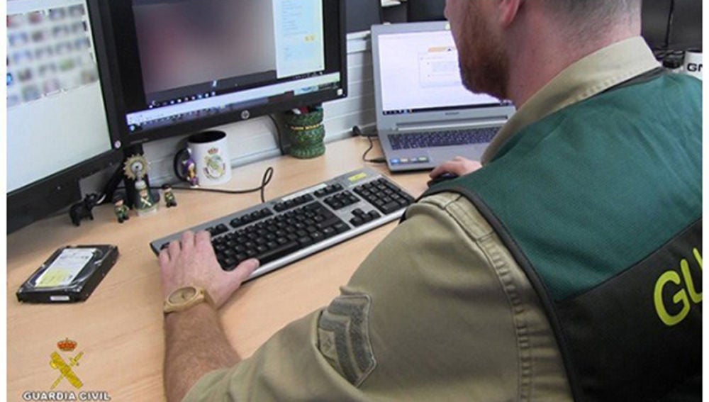 Un agente de la Guardia Civil analizan las fotografías que tenía el depredador sexual detenido