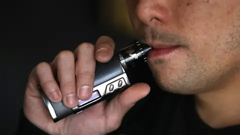 Un hombre fumando de un cigarro electrónico Un hombre fumando de un cigarro electrónico