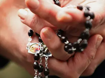 Una mujer con un rosario en las manos Una mujer con un rosario en las manos