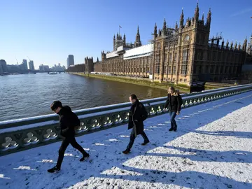 Varios viandantes caminan por la nieve sobre el Puente de Westminster Varios viandantes caminan por la nieve sobre el Puente de Westminster