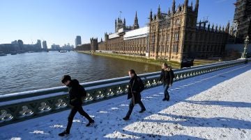 Varios viandantes caminan por la nieve sobre el Puente de Westminster