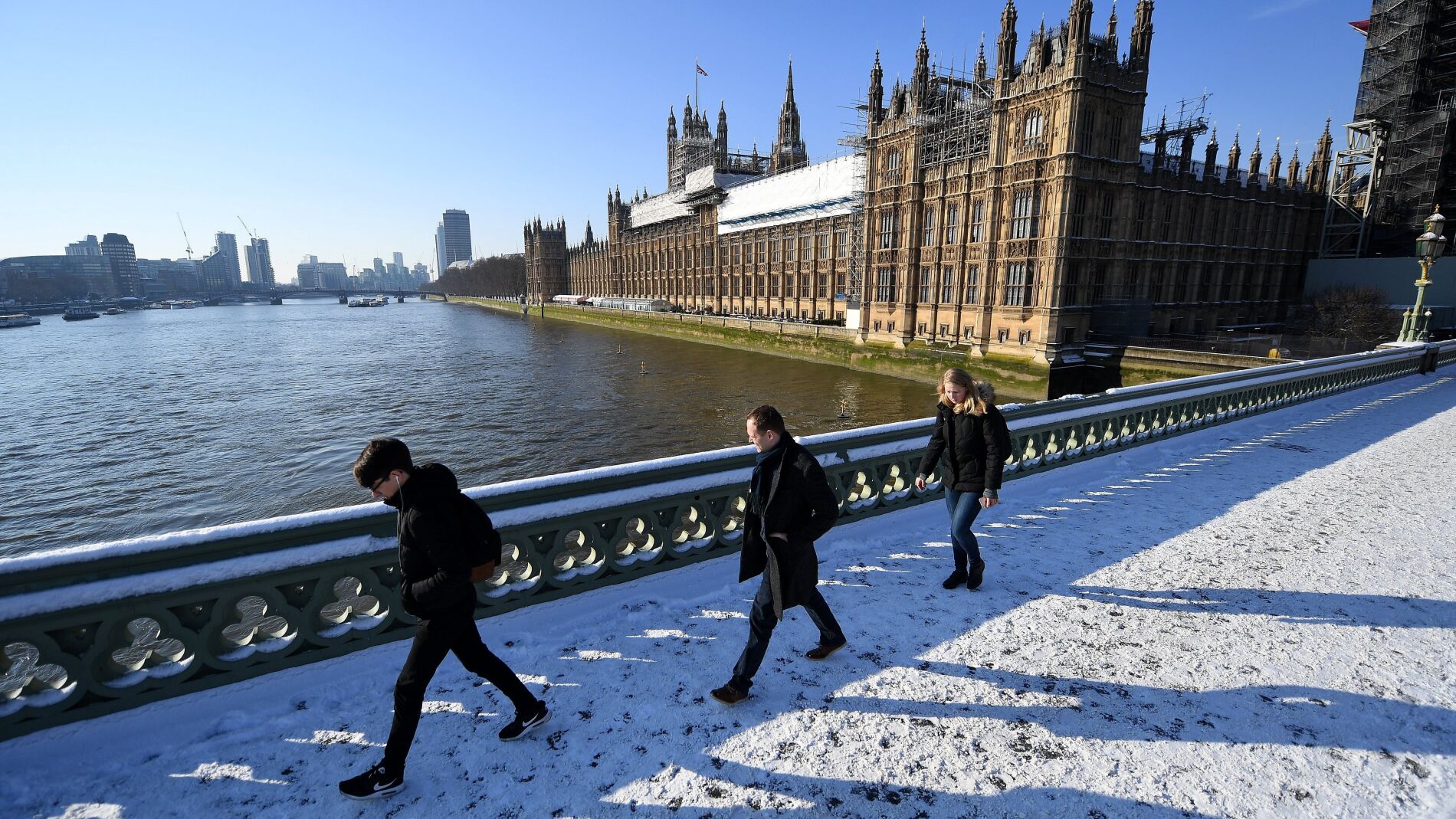 Varios viandantes caminan por la nieve sobre el Puente de Westminster