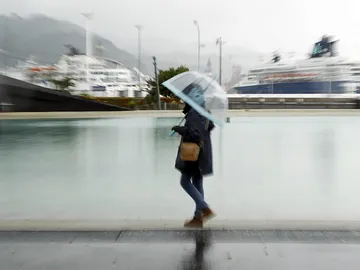 Una mujer paseando bajo la lluvia Una mujer paseando bajo la lluvia
