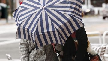 Dos mujeres se protegen con un paragüas de la lluvia y el viento en Pamplona