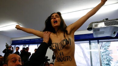 Una activista de Femen con el pecho desnudo interrumpe a Berlusconi mientras depositaba su voto en Milán