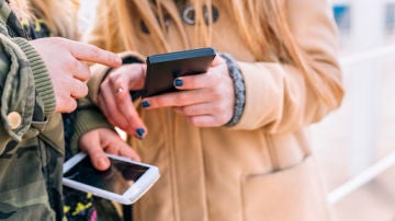 Imagen de archivo de dos j&oacute;venes mirando sus m&oacute;viles