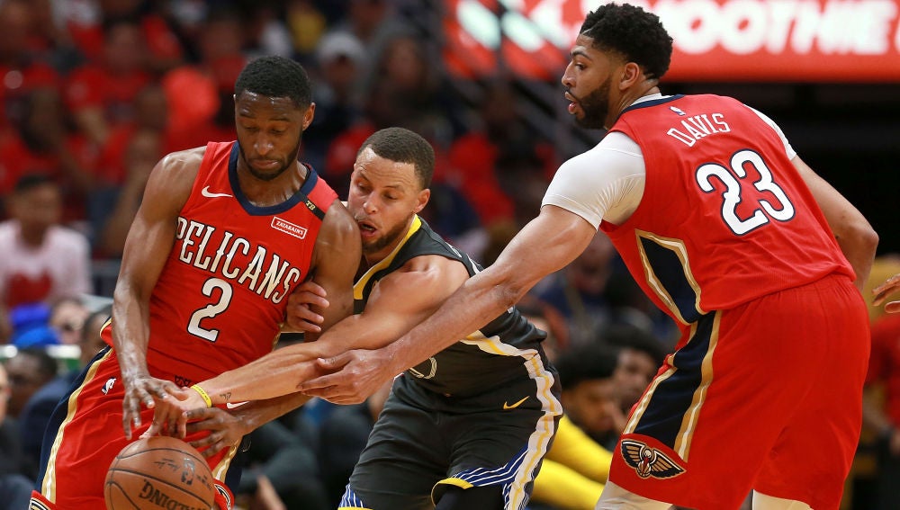 Curry intenta robar el balón entre Holiday y Davis