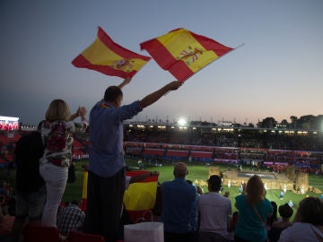 Dos personas agitan banderas al paso de los atletas españoles durante la inauguración de los XVIII Juegos Mediterráneos